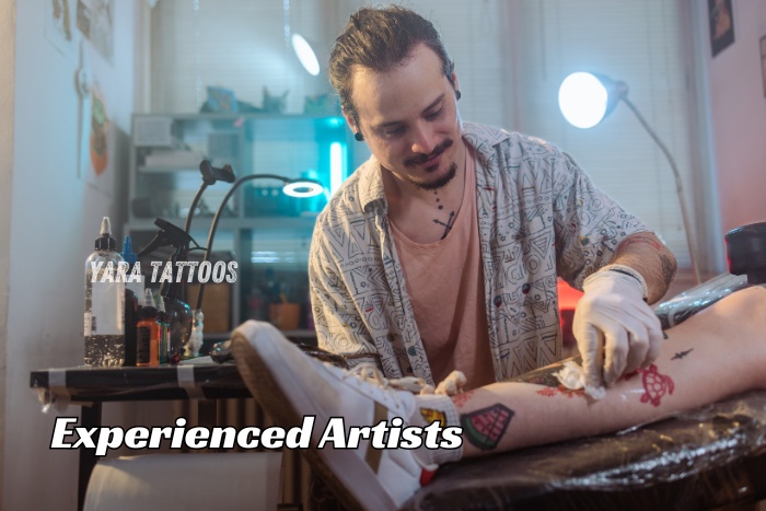 A skilled artist from Yara Tattoos in Coimbatore is focused on creating a custom leg tattoo in a professional studio setting